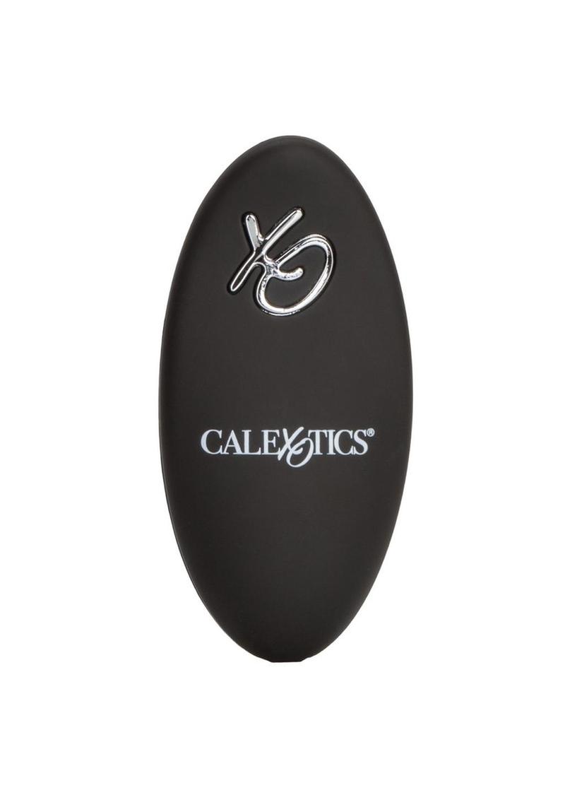 A black remote control. The remote is oval-shaped with a prominent brand logo displaying "calexotics."  There is only one button on the remote, which is silver, and shaped like the letters XO.